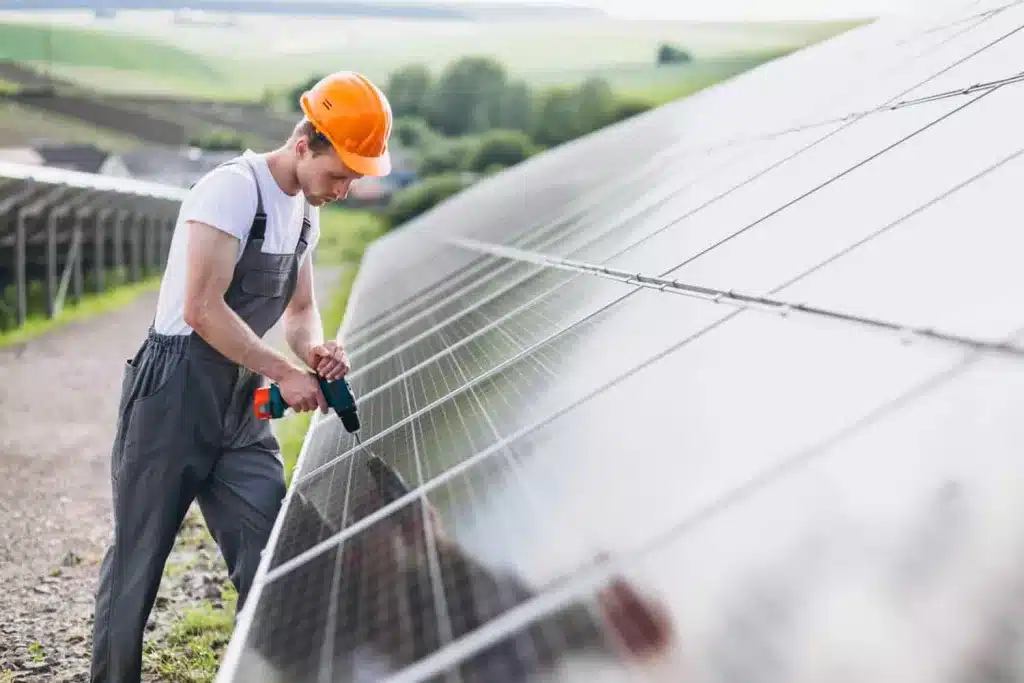 Grants for renewable energy in Wales. Man with drill in solar field